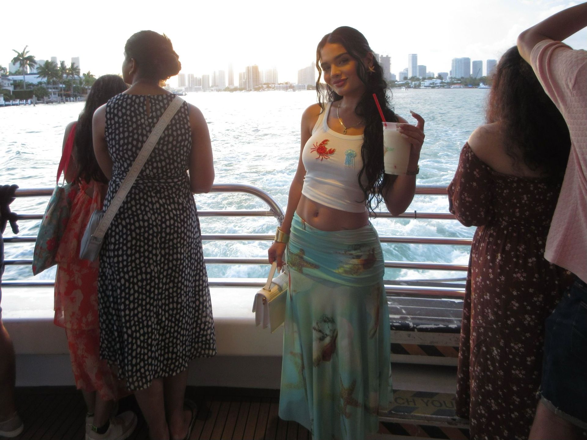 Passenger in the Miami Boat tour with the Miami Skyline behind them, holding a drink from the Mojito Bar on board part of the Miami Bus tour and Boat Combo