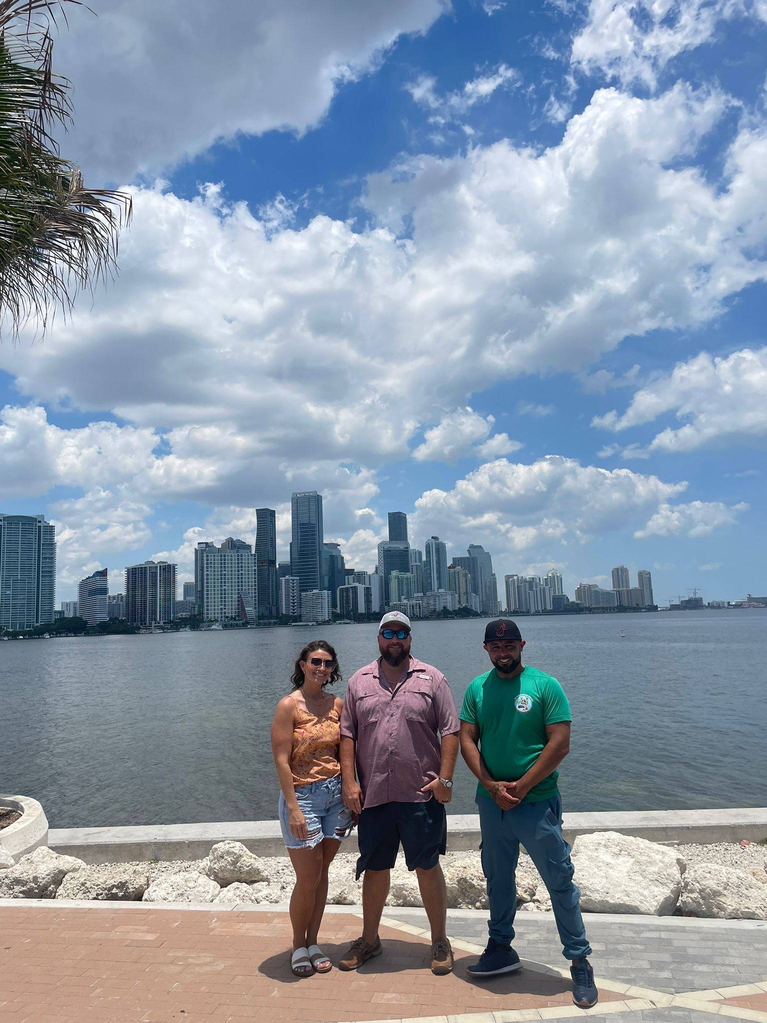 Miami Bus tour Tour Guide taking photos with passengers with the Miami Skyline in the Background. 
