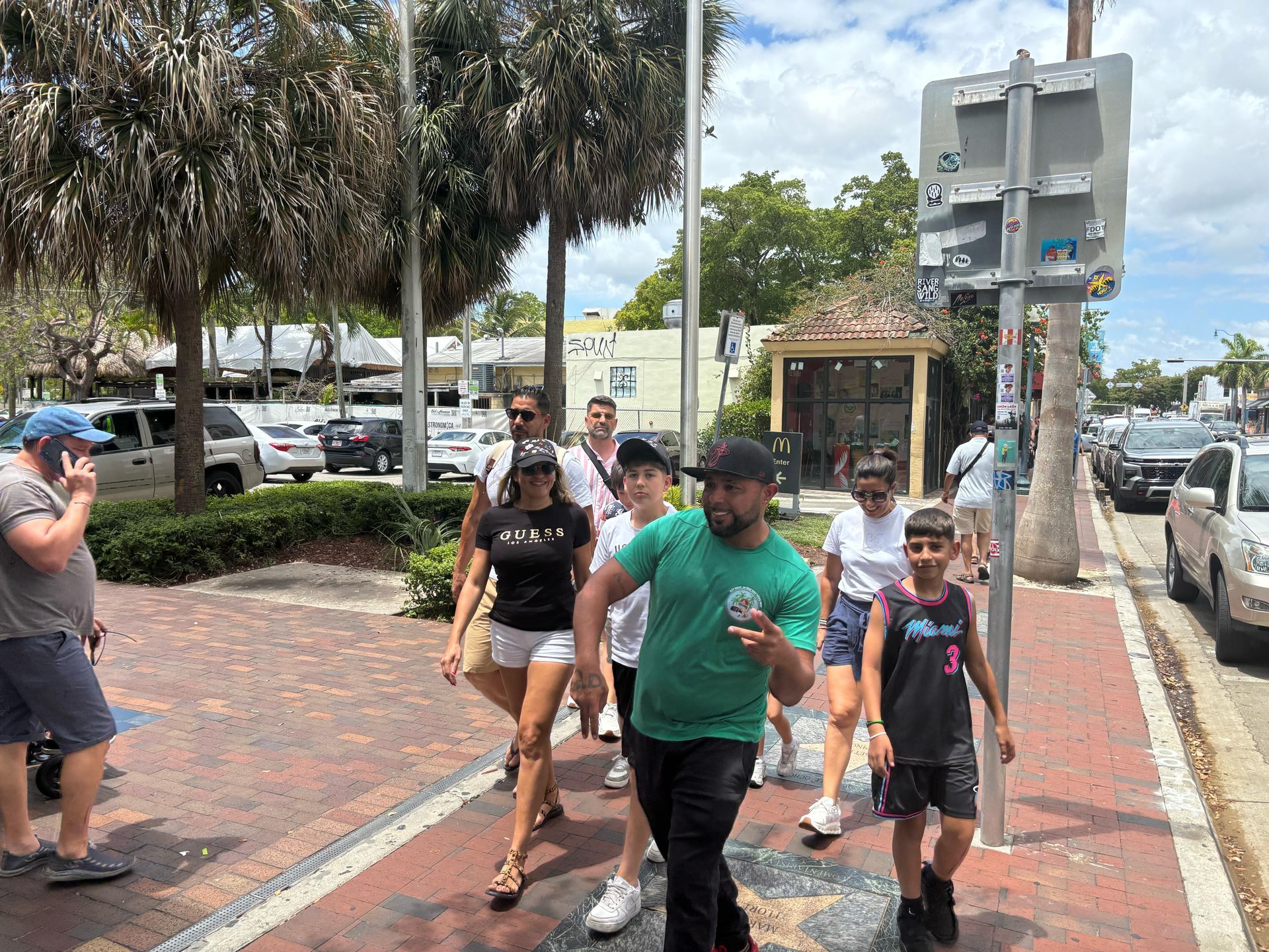 Guests walking through Little Havana during the Best Miami Tour Bus walking tour, guided by a local expert wearing a green tour shirt.
