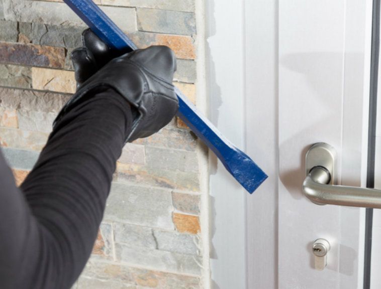 A person is breaking into a door with a crowbar