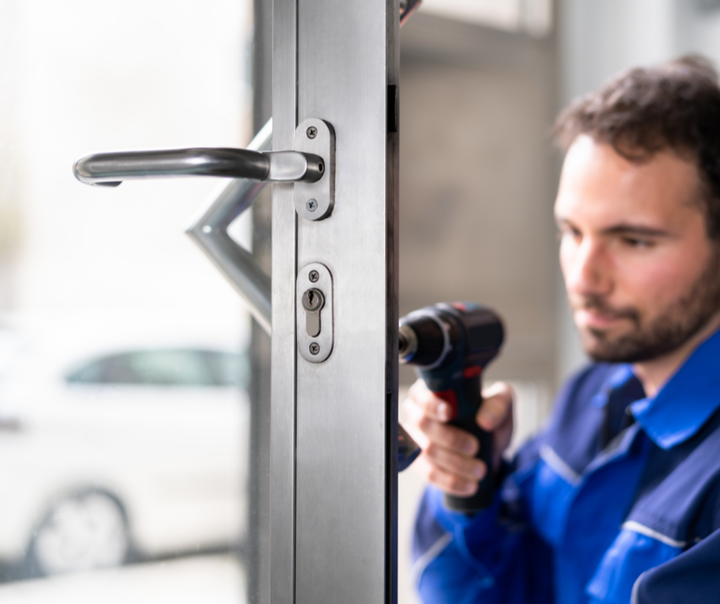 A man is fixing a door handle with a drill.