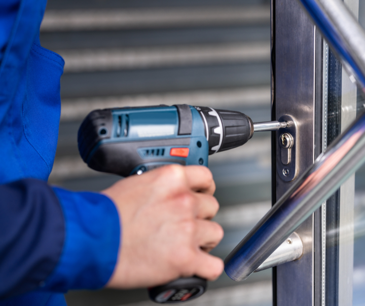 A man is using a drill to fix a door lock.