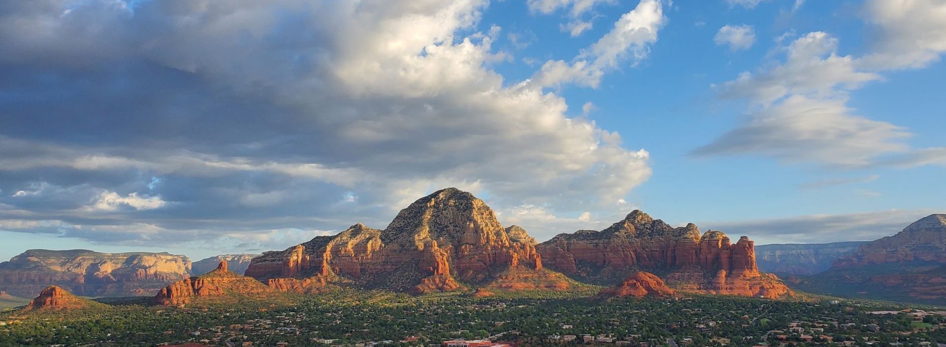 A mountain range with a city in the foreground and a cloudy sky in the background.