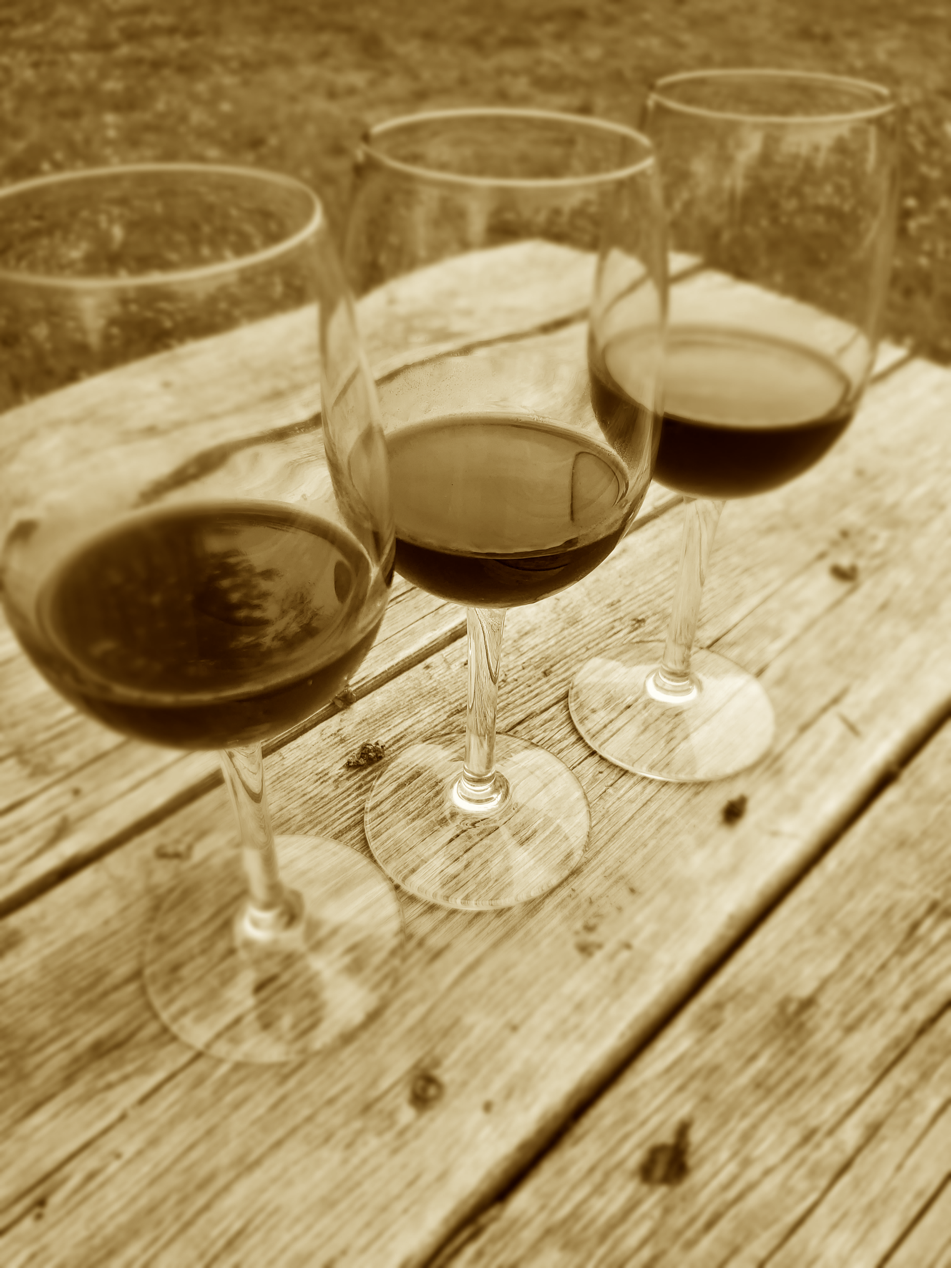 three wine glasses sitting on a wooden table