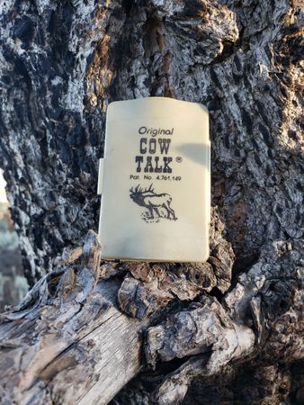 A cow talk box is sitting on a tree trunk