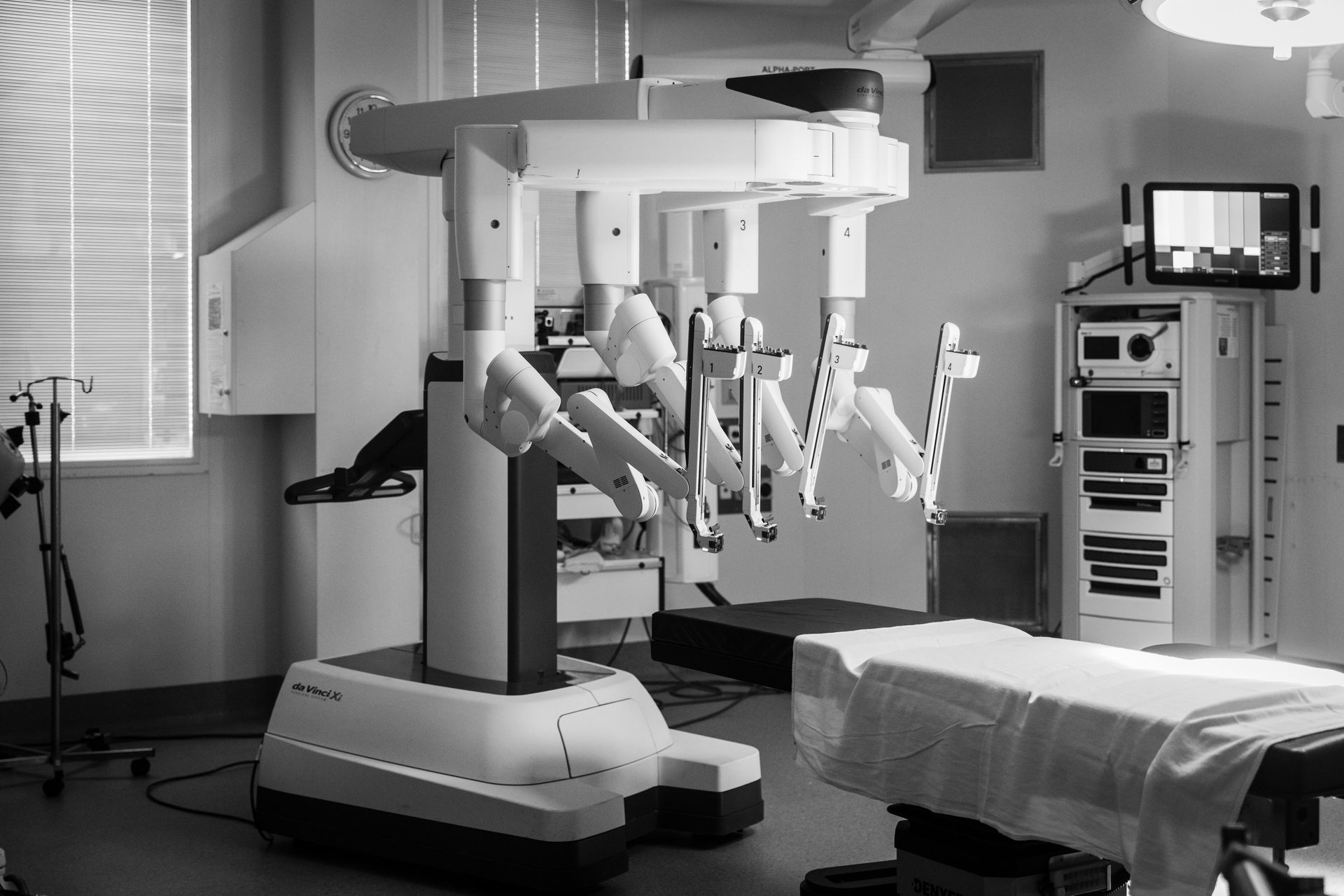 A black and white photo of an operating room with a robotic arm.