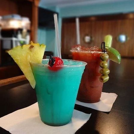 a pair of colorful fruity cocktail drinks on the counter at the bar
