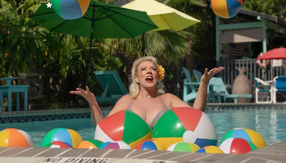 a woman in a bikini is floating in a swimming pool surrounded by beach balls .