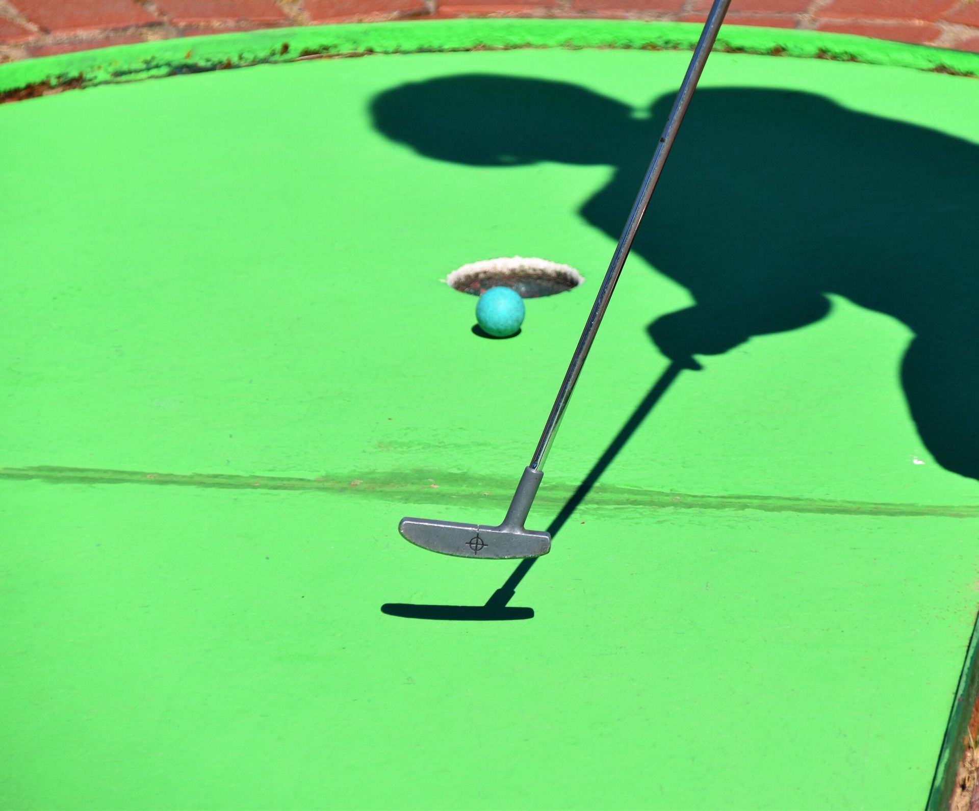a person is putting a golf ball on a green mat