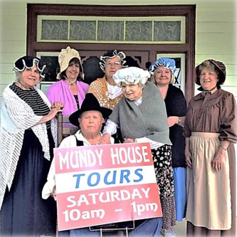 A group of people holding a sign that says Mundy House Tours