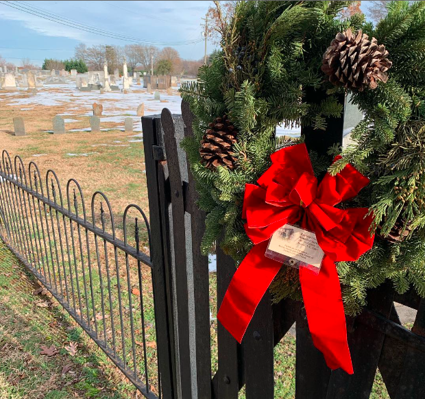 A Christmas wreath with pine cones and a red bow