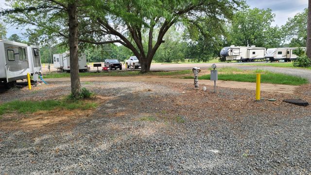 A group of rvs are parked in a gravel lot.