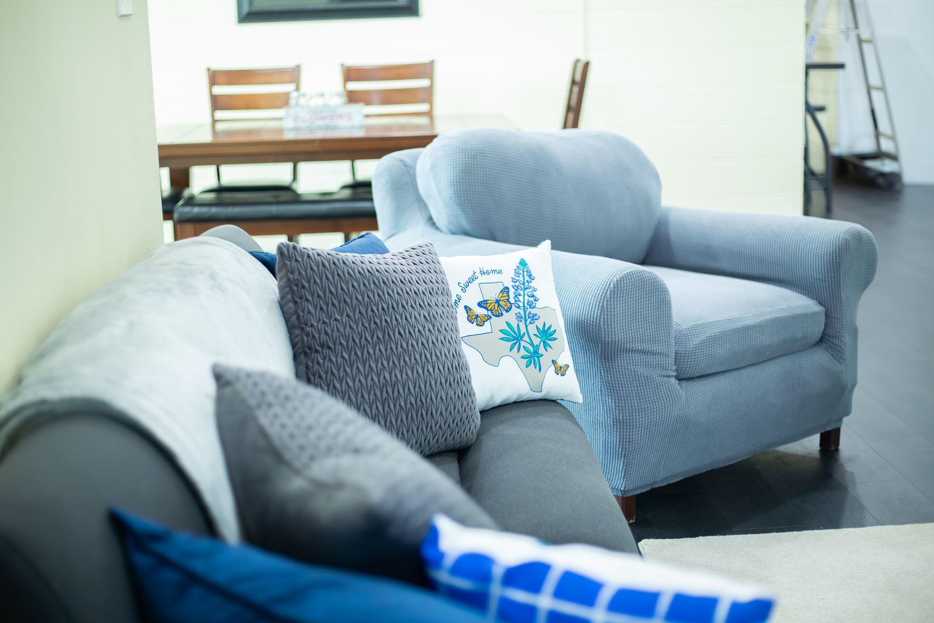 A living room with a couch and chair with blue pillows