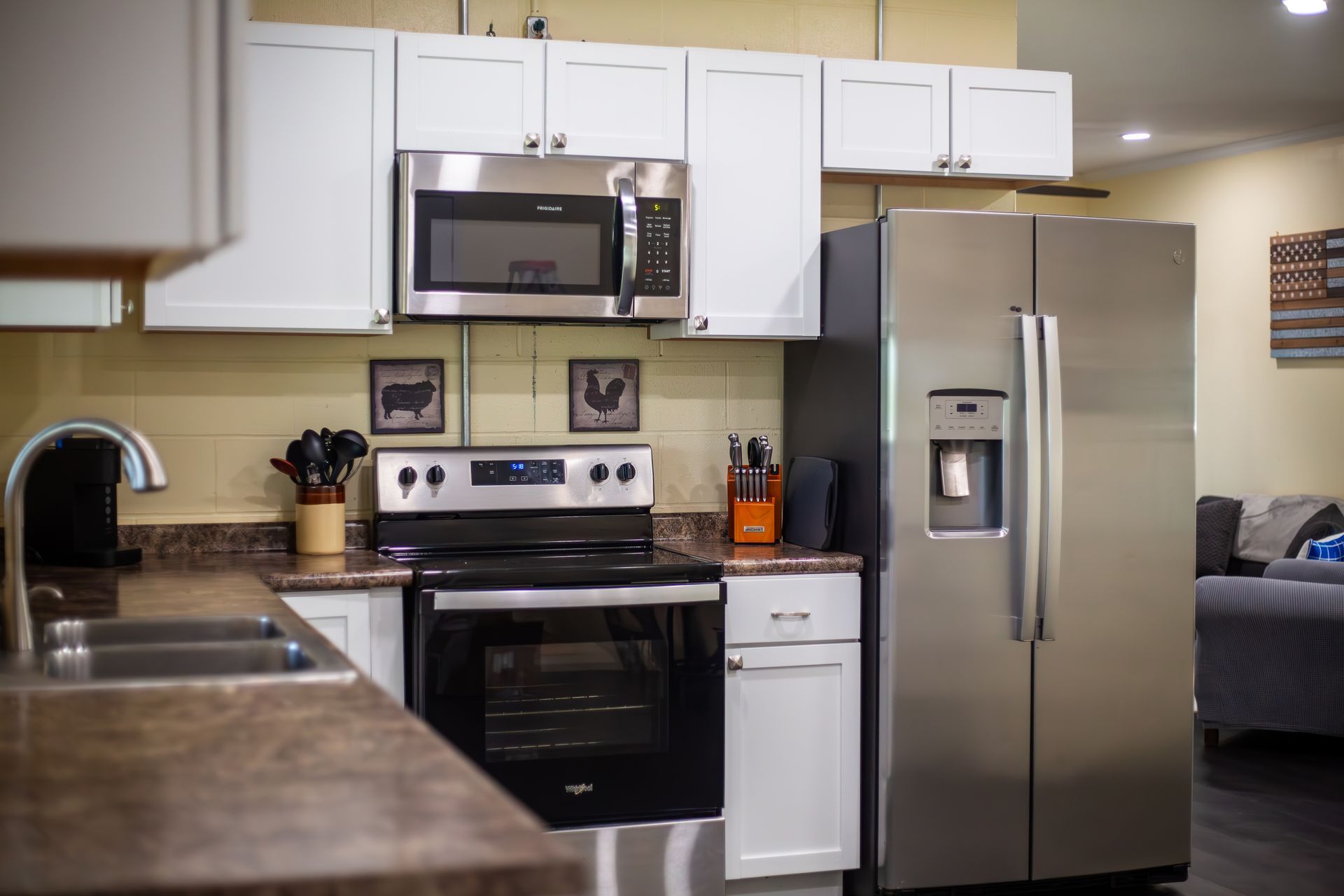 A kitchen with a stove , refrigerator , microwave and sink.