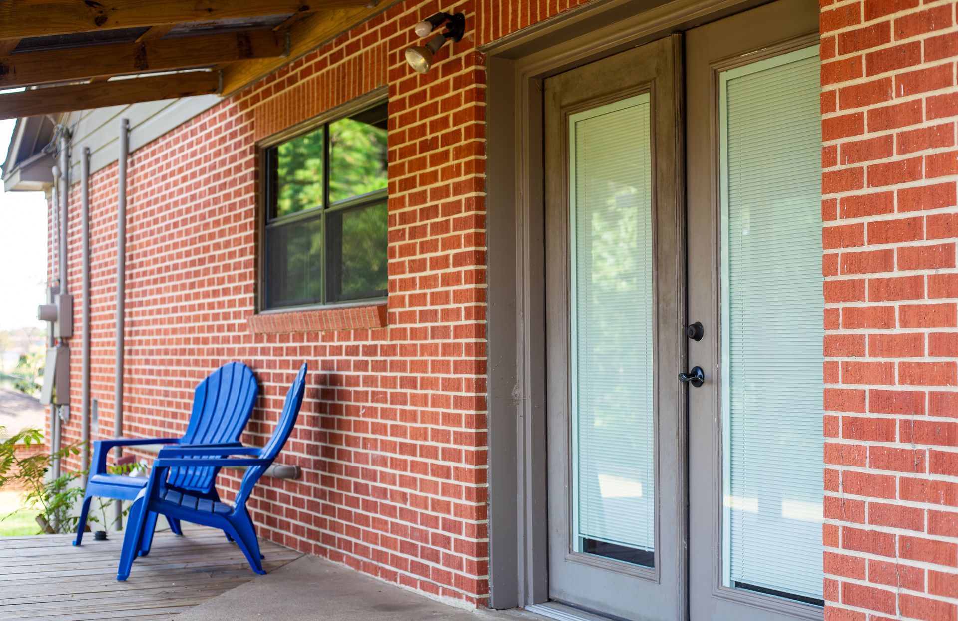 A blue chair is sitting on the porch of a brick house.