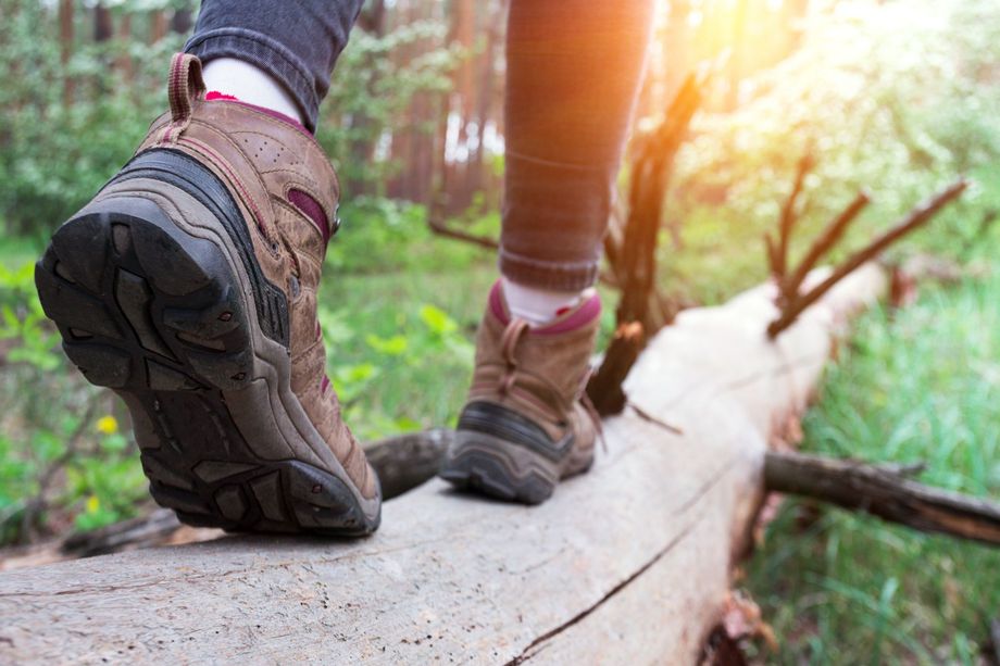 A person is walking on a log in the woods.