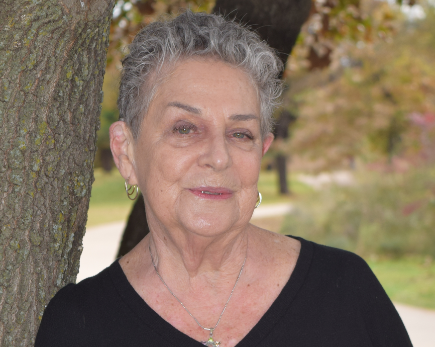 A woman in a black shirt is leaning against a tree.