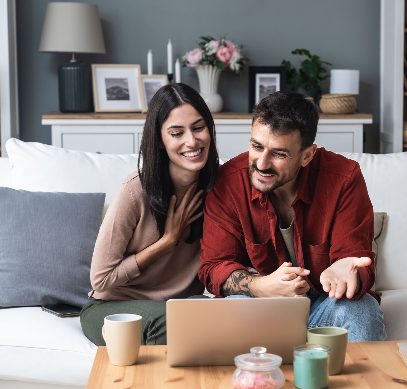 A man and a woman are sitting on a couch looking at a laptop.