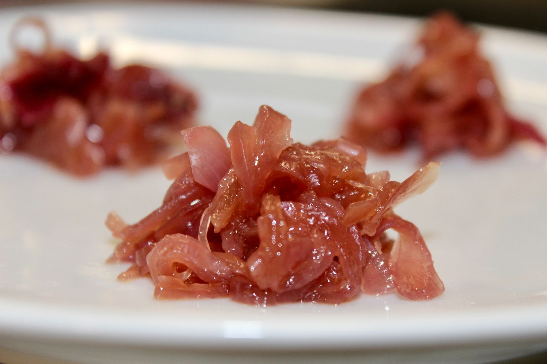 Cipolle rosa sottaceto su un piatto bianco, tre mucchietti di diverse dimensioni.