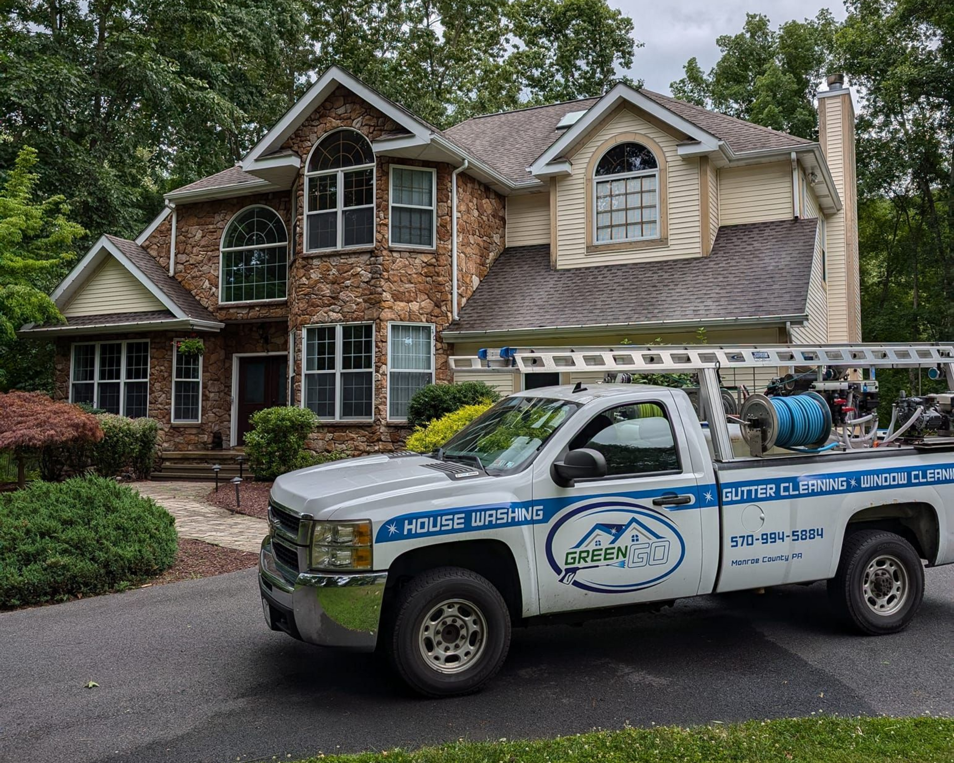 A truck with a company logo is parked in front of a two-story house with a brick facade.