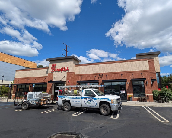 Chick-fil-A restaurant with a white service truck and trailer parked in front under a blue sky.