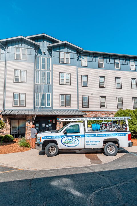 White service truck parked in front of a light blue and gray apartment building; person standing by the truck.