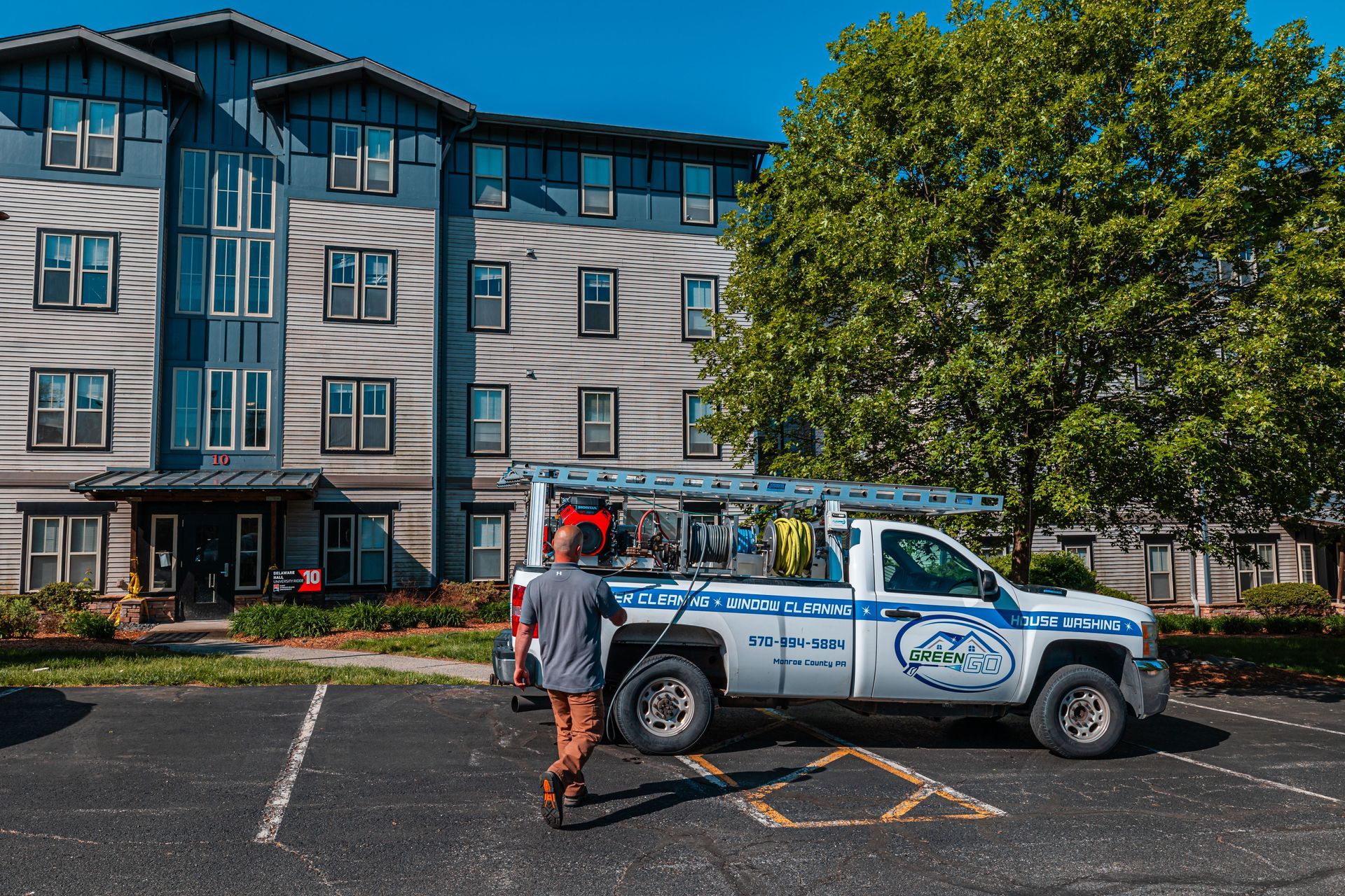 A person walks towards a work truck parked in front of an apartment building.