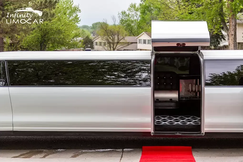White limousine with open door and red carpet. Interior shows beverage storage.