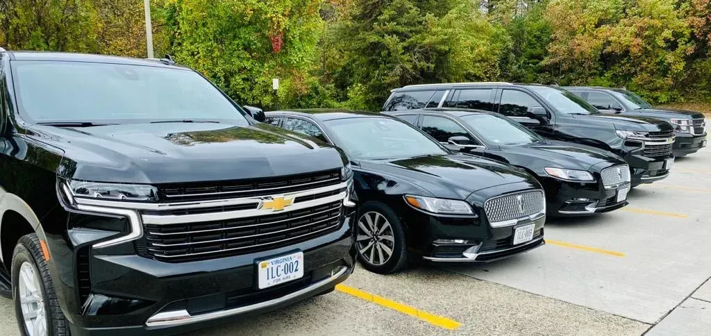 Black SUVs and sedans parked in a row, likely for a transportation service.
