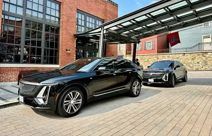 White Ford Transit van parked outside a store on a sunny day. A black pickup truck is in the background.