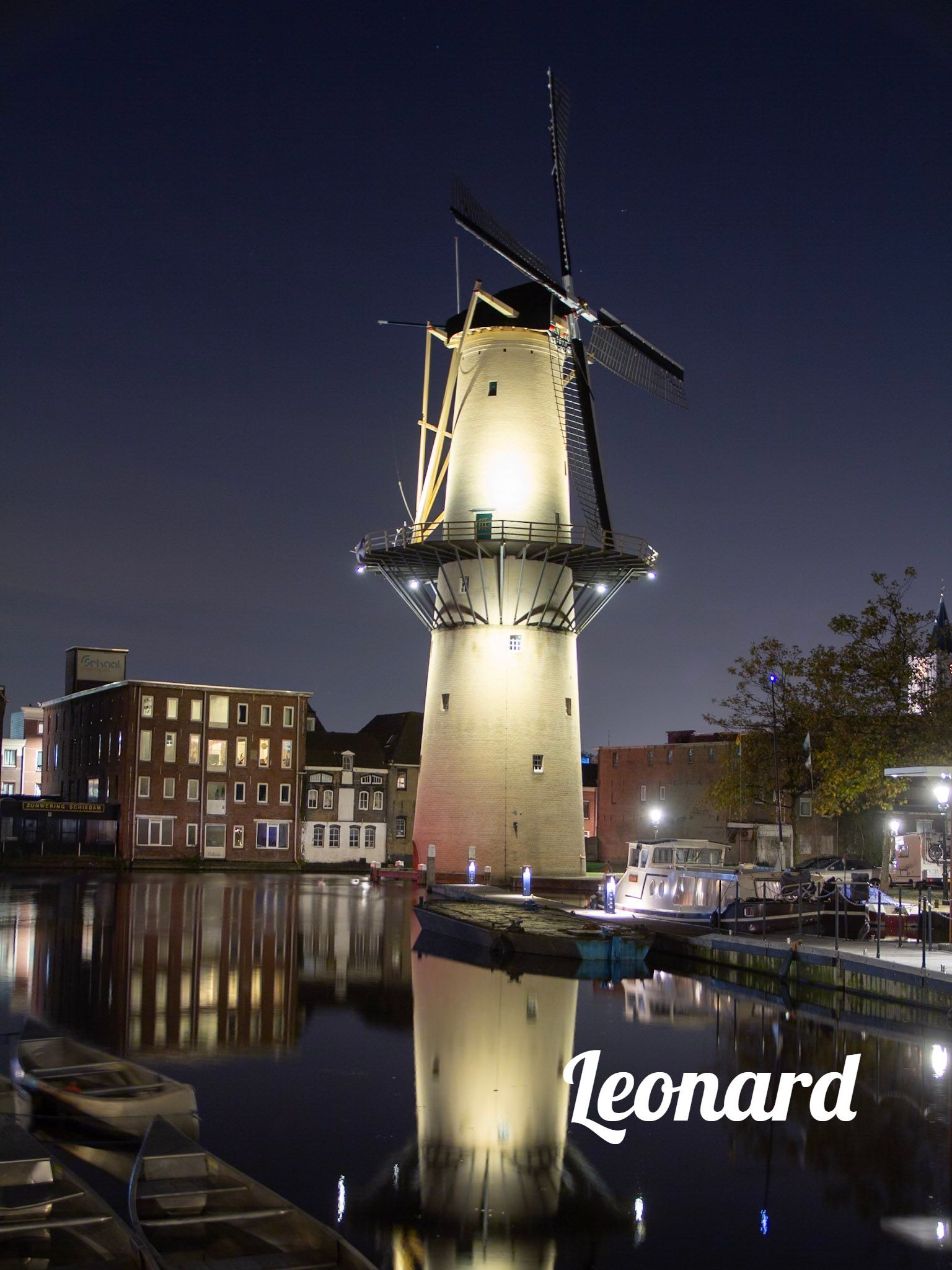 Een windmolen is 's nachts verlicht in een stad