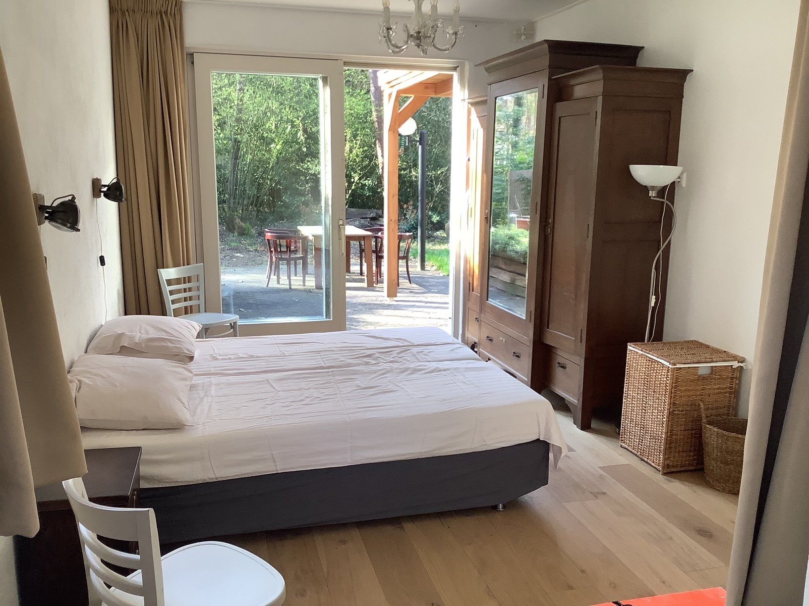 Zicht op de hoofd slaapkamer met dubbel bed, antieke kast en zicht op de schuifpui.