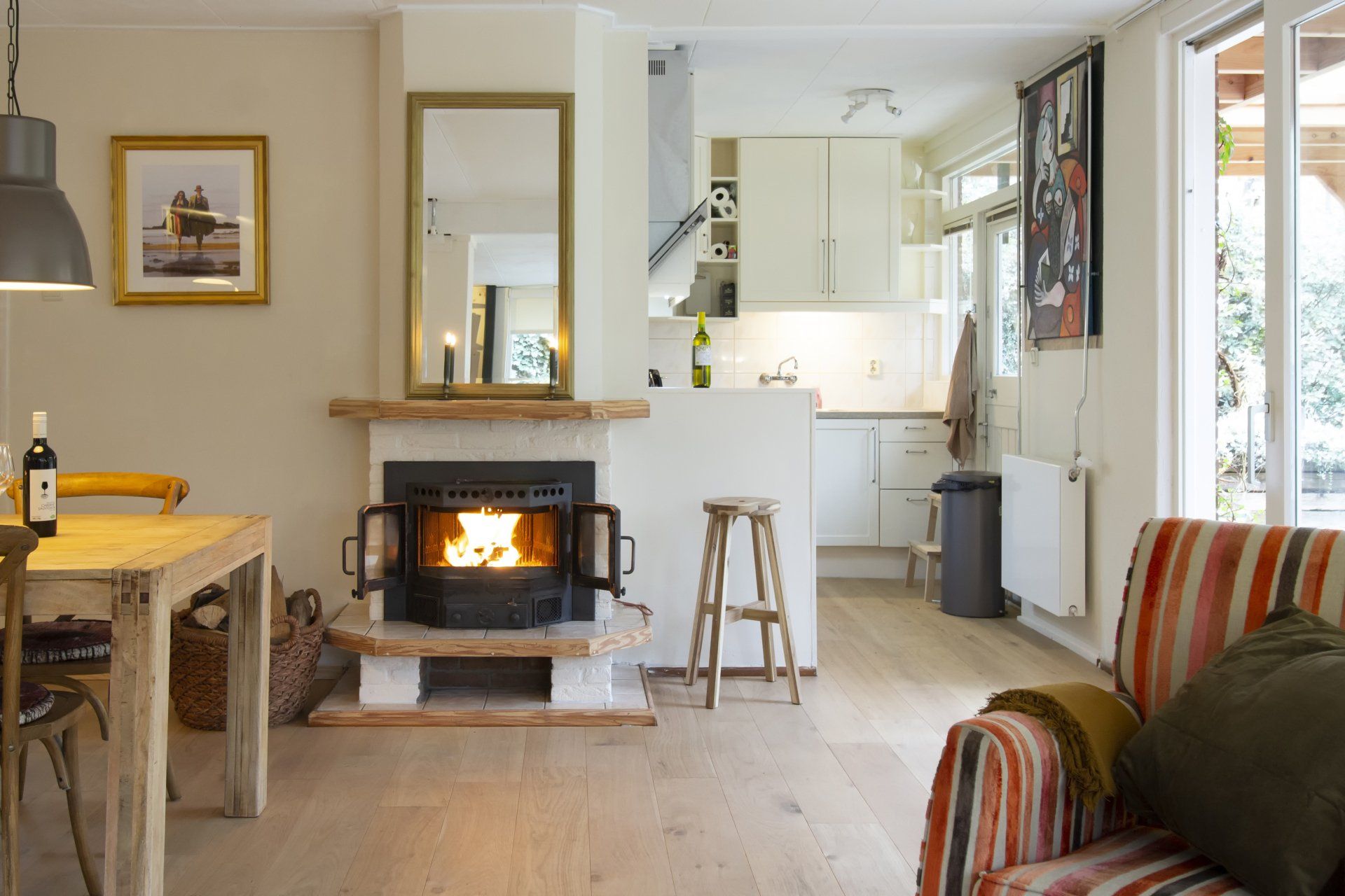 Zicht op de keuken en de houtkachel vanaf de bank in de woonkamer.