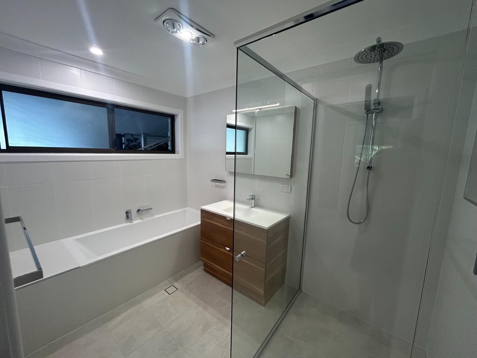 A Bathroom With a Bathtub , Sink , Shower and Mirror — BK Build Group in Sawtell, NSW