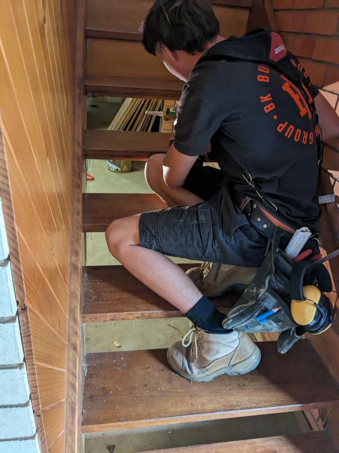 A Man is Sitting on a Set of Wooden Stairs — BK Build Group in Coffs Harbour, NSW
