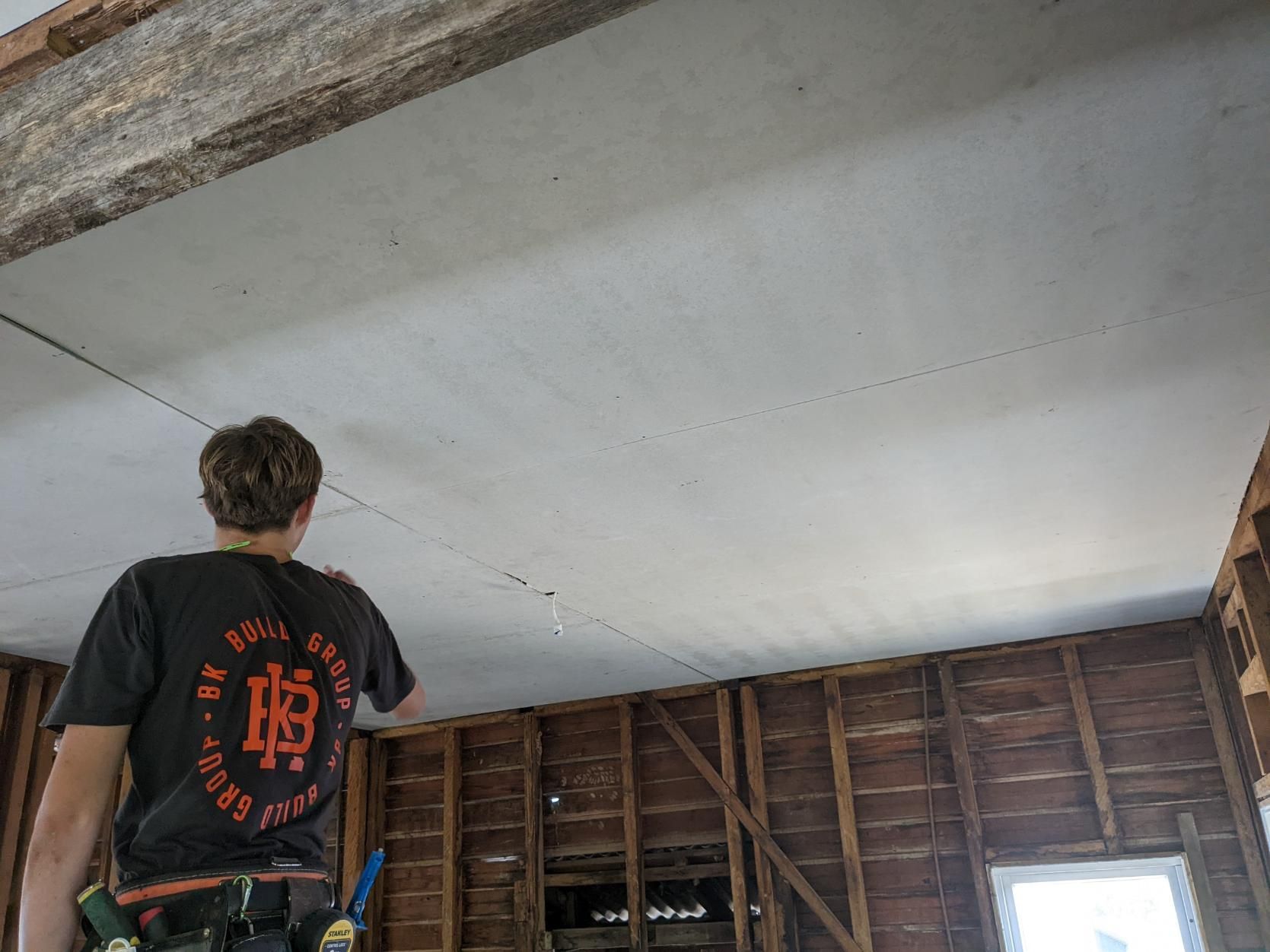 A Man is Standing in a Room Looking Up at the Ceiling — BK Build Group in Coffs Harbour, NSW