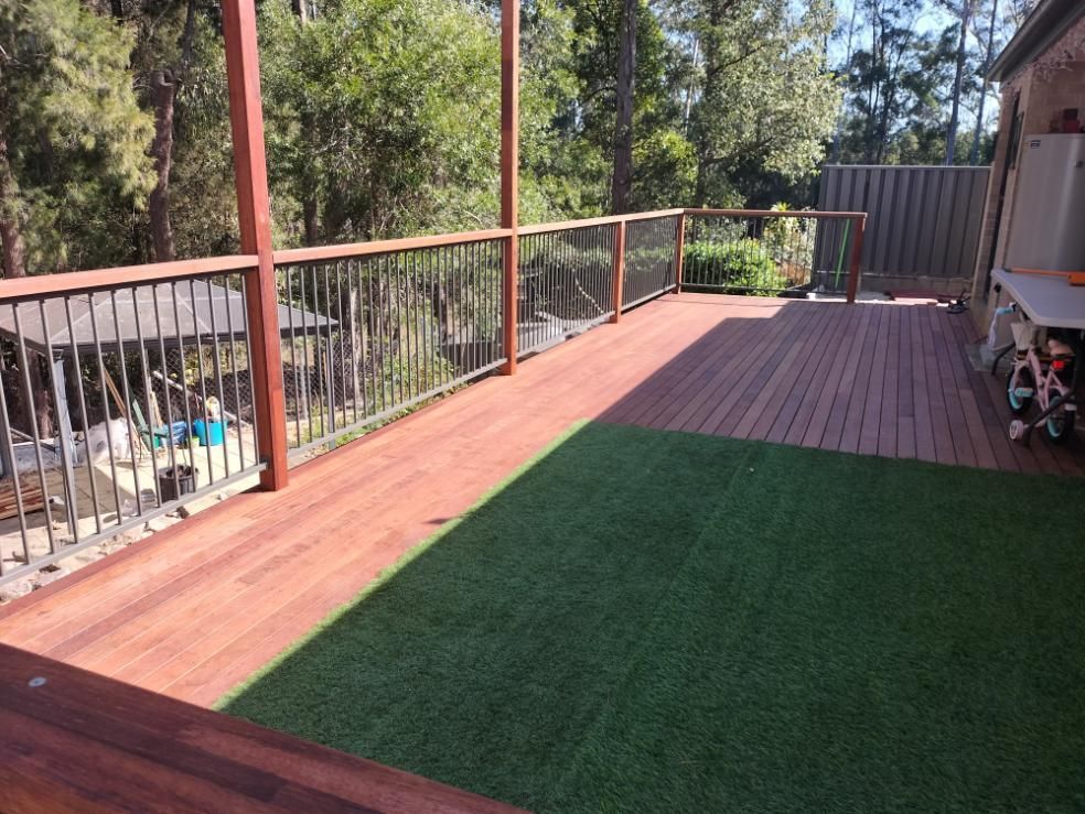 A Wooden Deck With a Metal Railing and a Lawn in Front of It — BK Build Group in Nambucca Heads, NSW