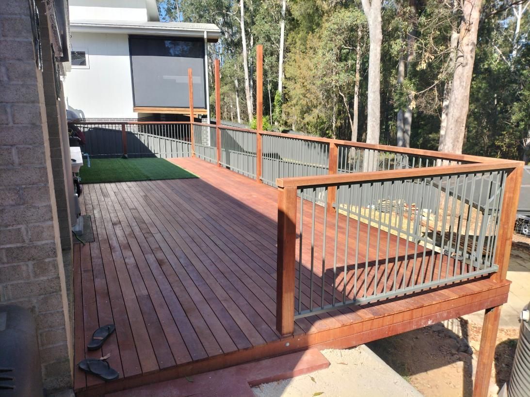 A Wooden Deck With a Metal Railing is Being Built in Front of a House — BK Build Group in Coffs Harbour, NSW