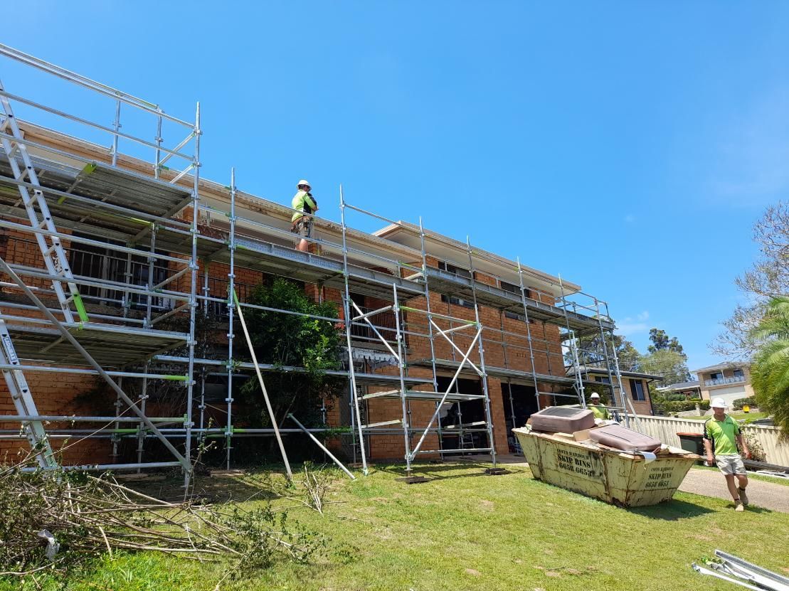 A Man is Standing on a Scaffolding on the Roof of a Building — BK Build Group in Sawtell, NSW