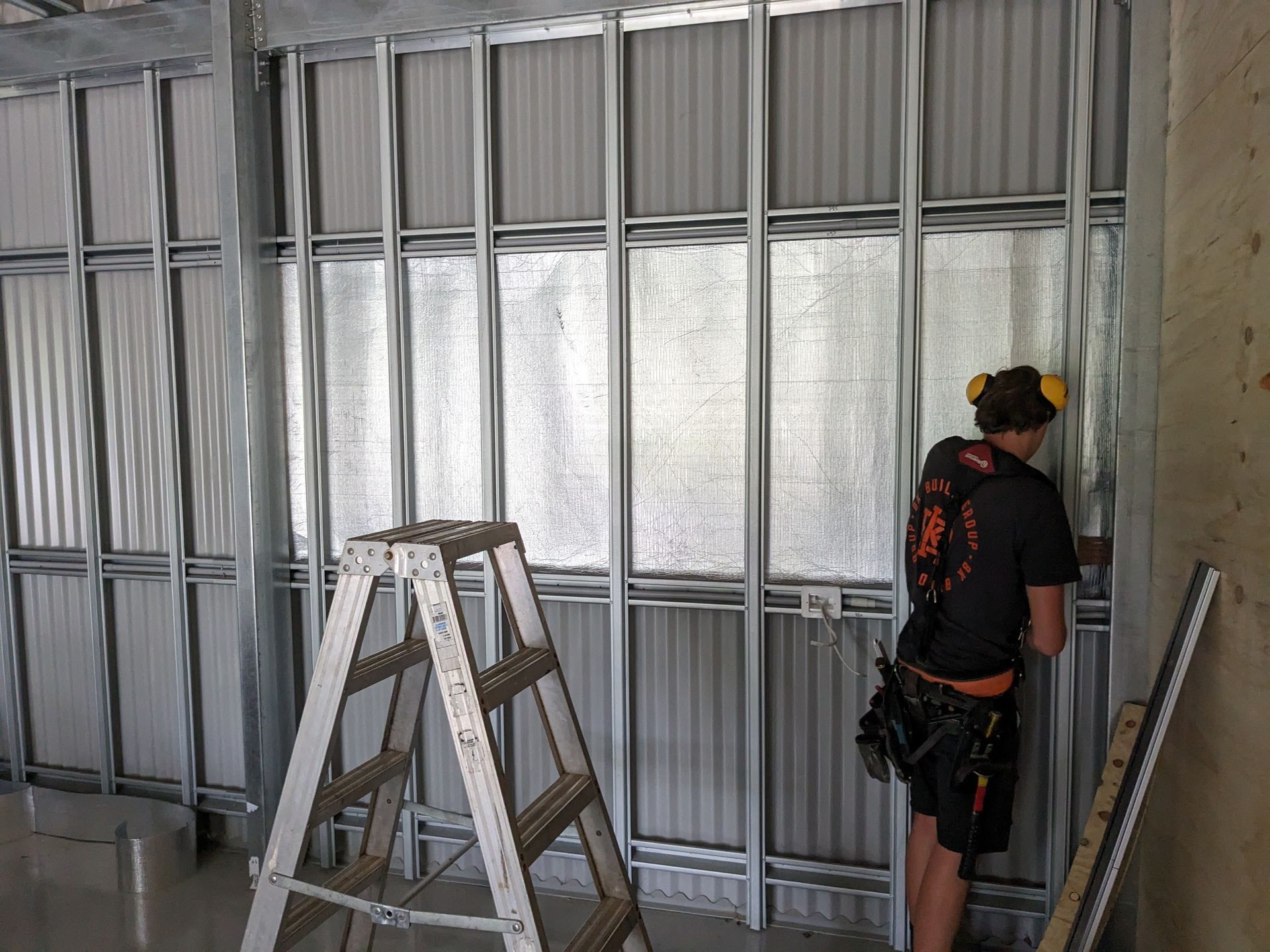 A Man is Working on a Wall Next to a Ladder — BK Build Group in Coffs Harbour, NSW