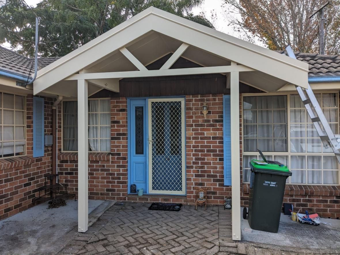 A Brick House With a Blue Door and a White Porch — BK Build Group in Coffs Harbour, NSW