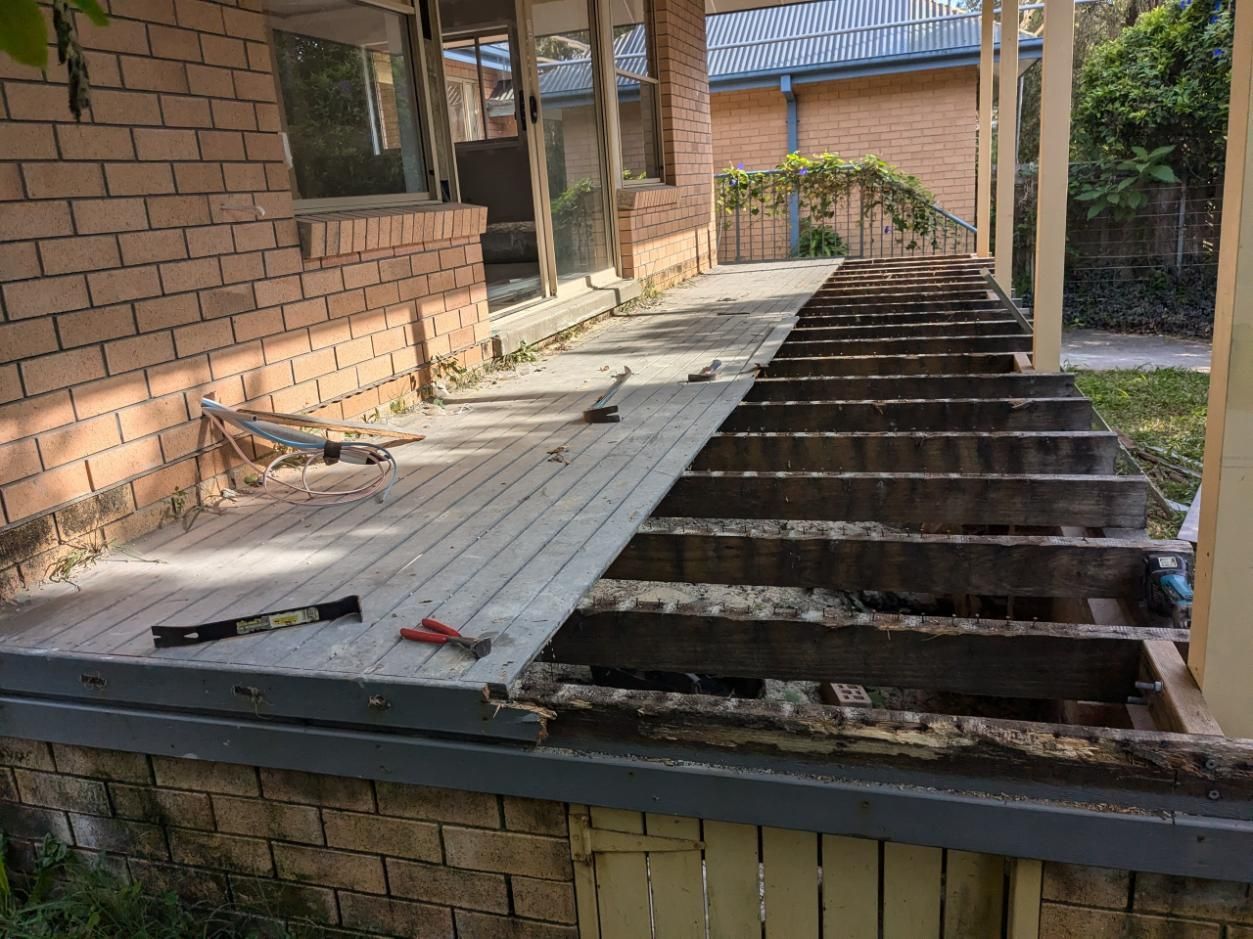 A Wooden Deck is Being Built on the Side of a Brick House — BK Build Group in Coffs Harbour, NSW