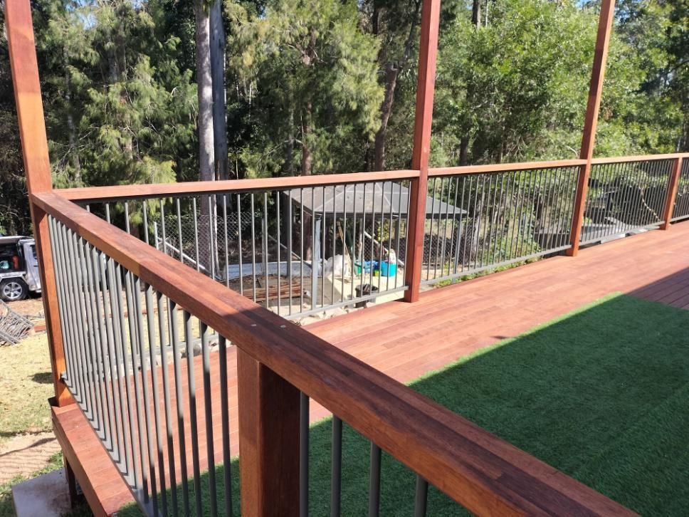 A Wooden Deck With a Metal Railing Surrounded by Trees — BK Build Group in Woolgoolga, NSW