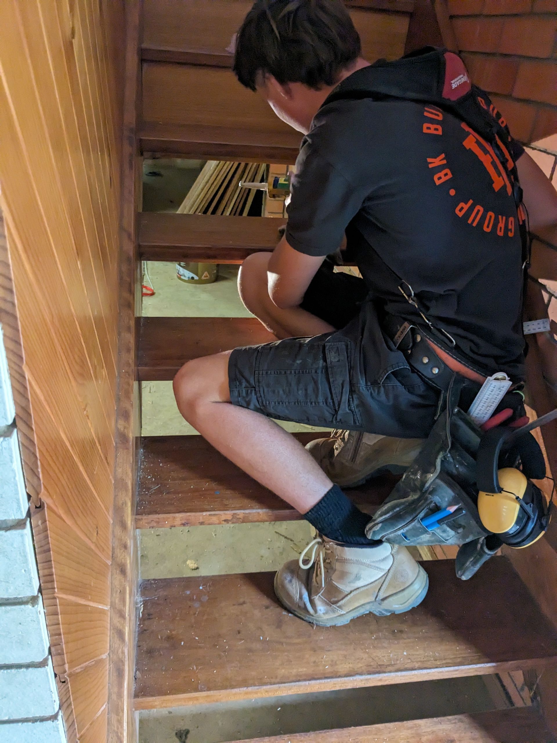 A Man is Sitting on a Set of Wooden Stairs — BK Build Group in Coffs Harbour, NSW