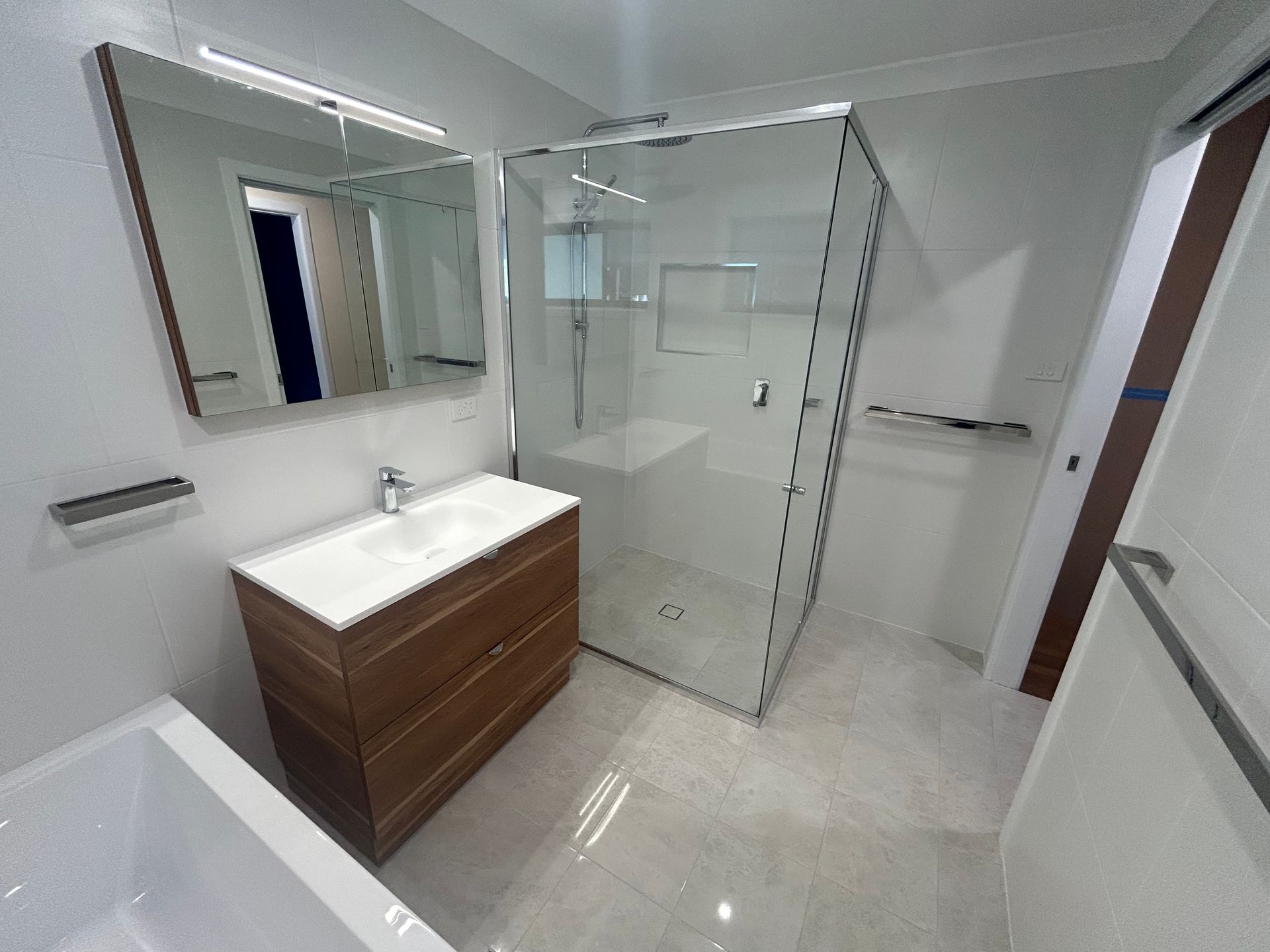 A Bathroom With a Sink , Mirror , and Walk in Shower — BK Build Group in Coffs Harbour, NSW