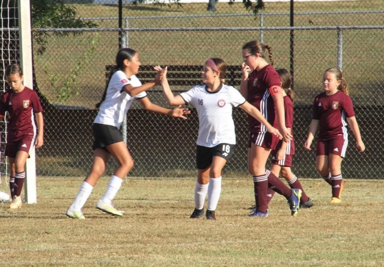 A group of young SCOR girls are playing soccer on a field