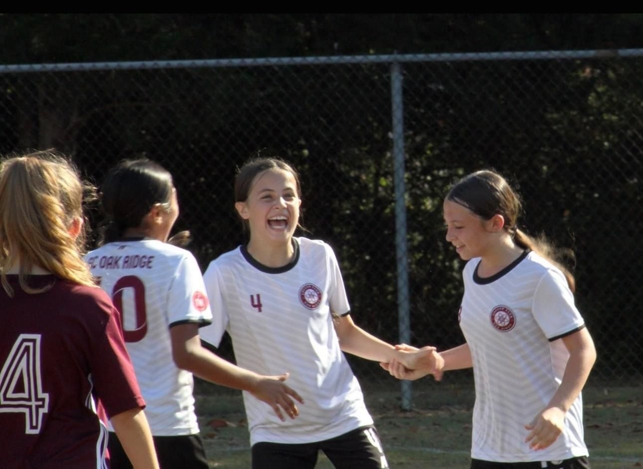 A girl with the number 4 on her shirt shakes hands with another girl