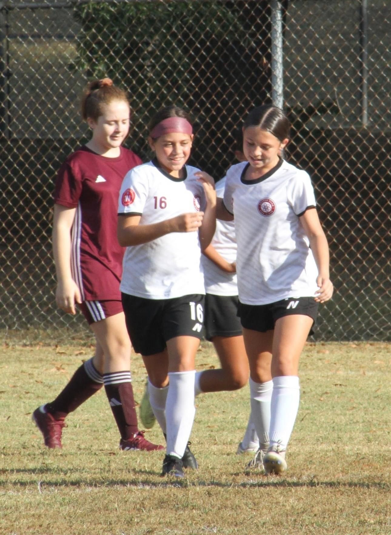 A group of SCOR female soccer players are walking on the field