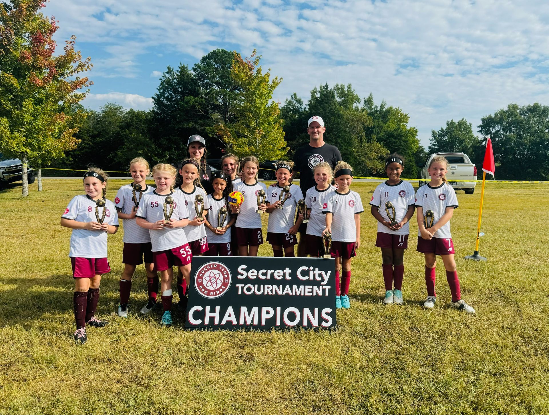 A group of young girls are posing for a picture in front of a sign that says secret city tournament champions.