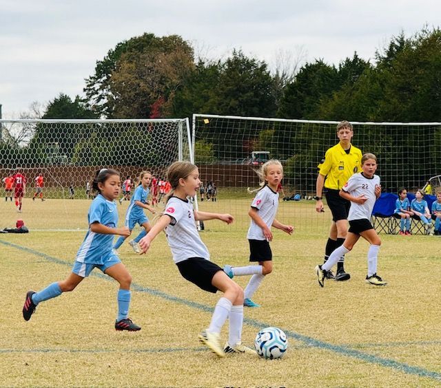 A group of young girls are playing soccer on a field.